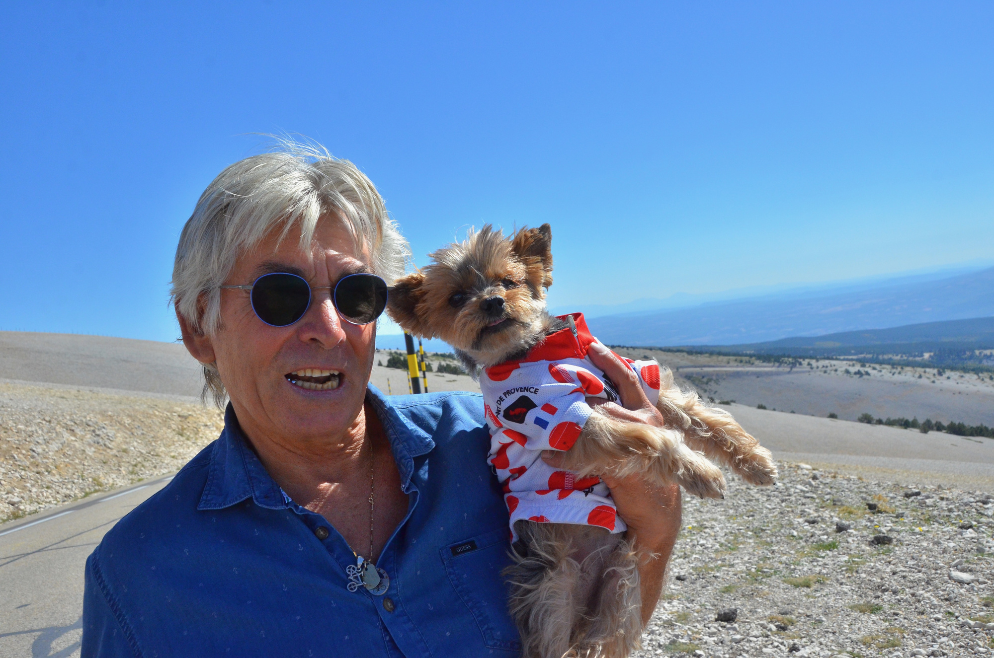 Une personne souriante tient son petit chien dans les bras.